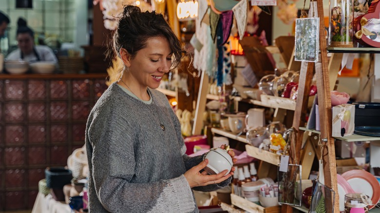 Woman holding a small ceramic item in a shop