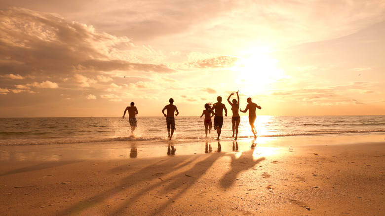 Friends running into the surf