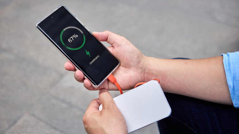 Person charging a phone with a power bank