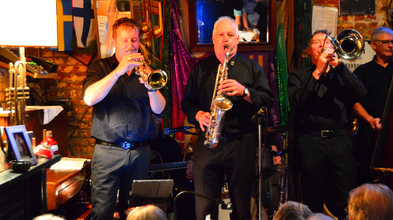 Three men with a trumpet, saxophone, and trombone playing in a jazz bar