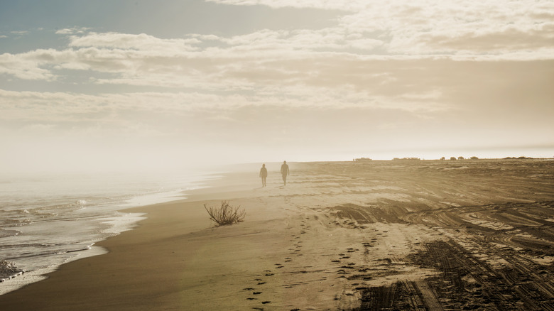 Two people walking along a misty Ocracoke Beach