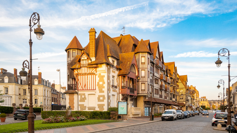 Old architecture in Deauville, France, with cars lining the street, lamp posts along the road and European architecture