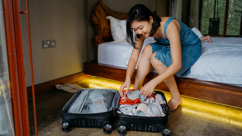 smiling woman packing suitcase