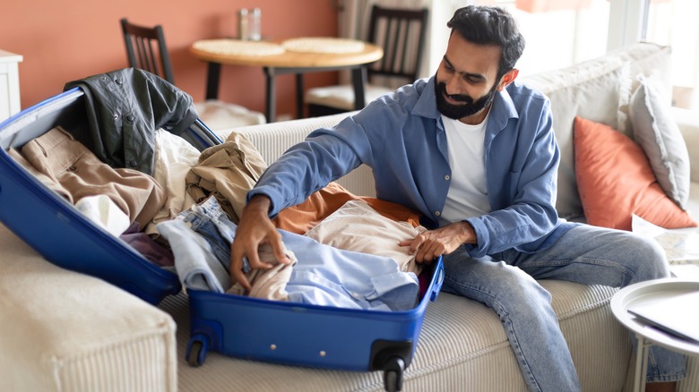 man packing clothes suitcase