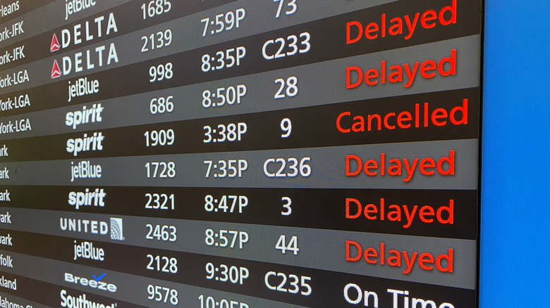 An airport board with flight delays and cancelations listed in red