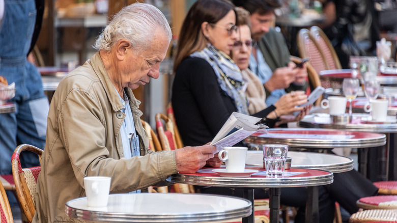 Man reading the paper quietly in Paris cafe
