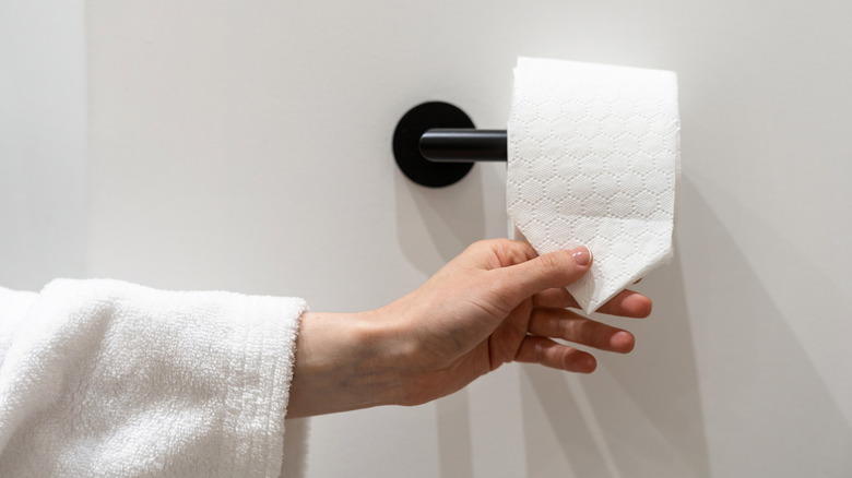 Hand reaching for toilet paper roll