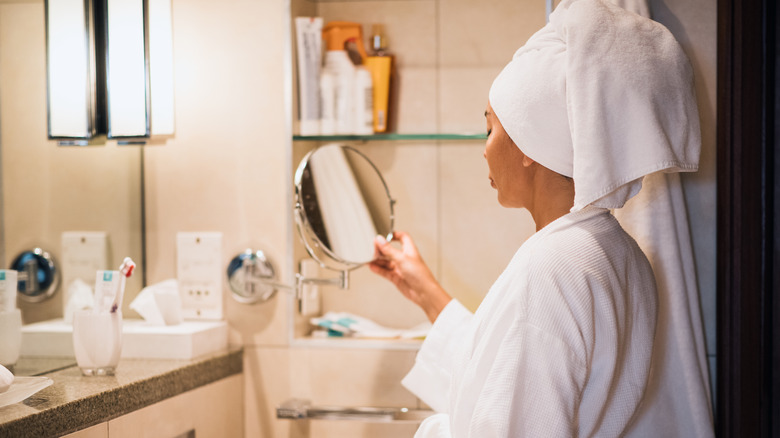 Woman looking in closeup mirror in the bathroom