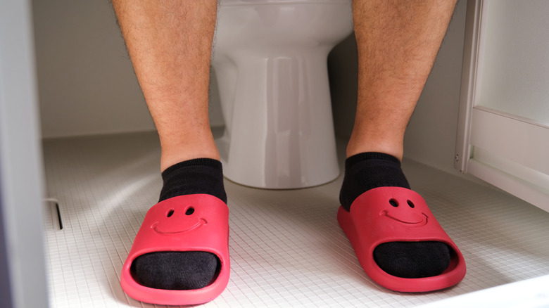 Feet with red smiley sliders in the bathroom