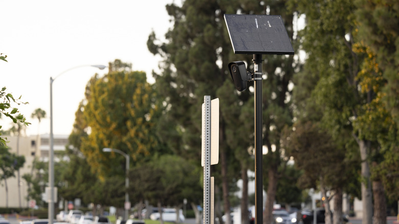 Flock camera on a pole high above a roadway with traffic