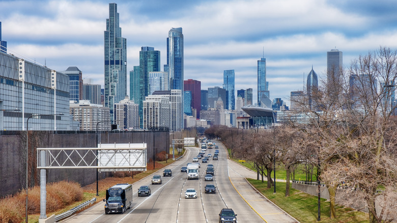 Cars driving on highway with Chicago skyline behind cloudy day
