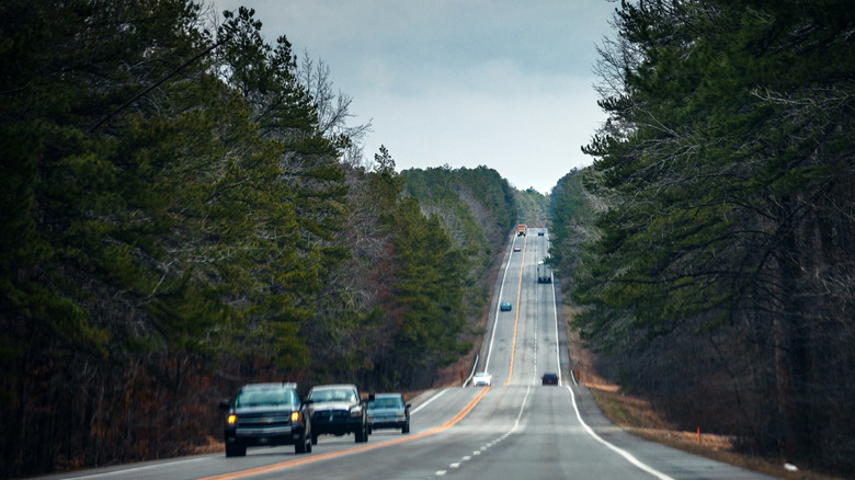 Cars driving on hilly road bordered by forests in Arkansas