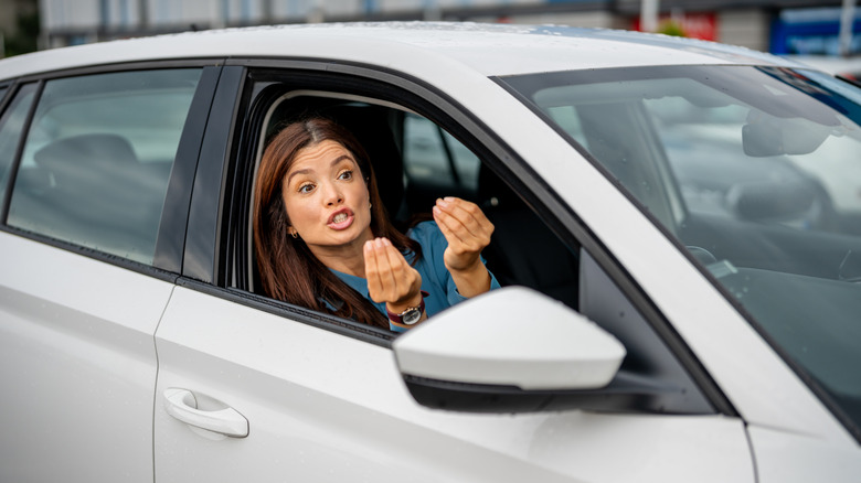 Woman making aggressive hand gestures from her car