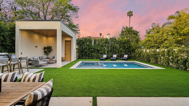 A backyard pool with a modern pool house and gardens