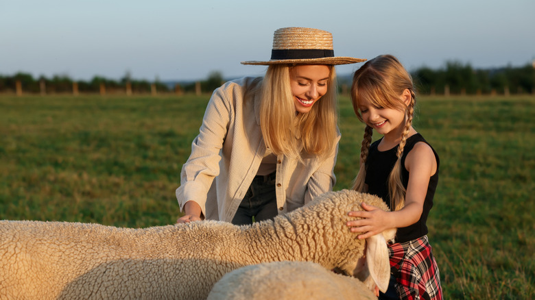 Mother and daughter petting a sheep at a farm