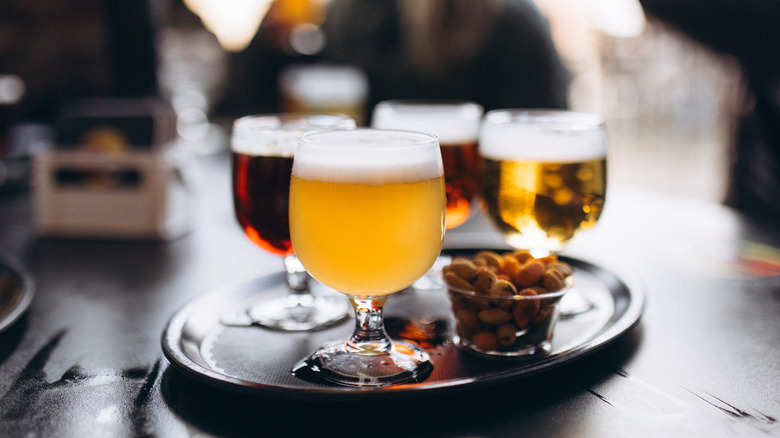 A sample of four different beers with a ramekin of nuts