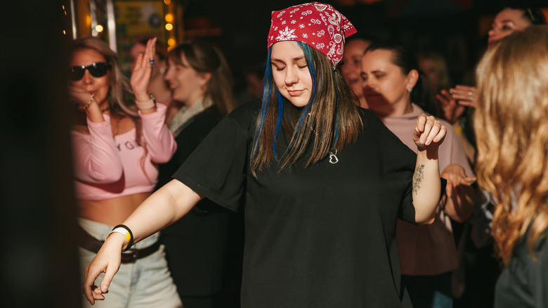 A woman dancing wearing a large baggy black t-shirt in a Berlin club