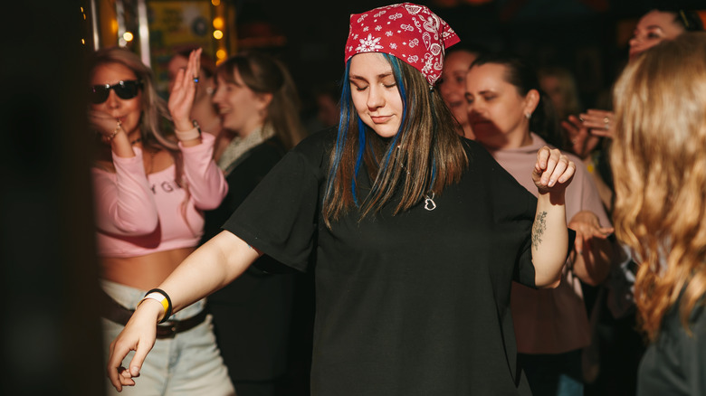 A woman dancing wearing a large baggy black t-shirt in a Berlin club