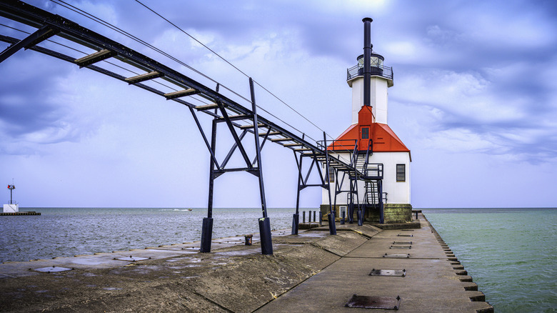 A white and red lighthouse connected to a walking bridge in St. Joseph, Michigan.