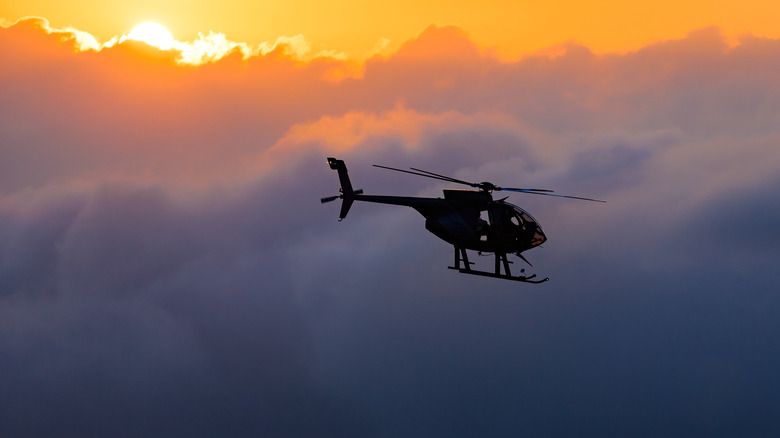 Helicopter flying against sunset clouds