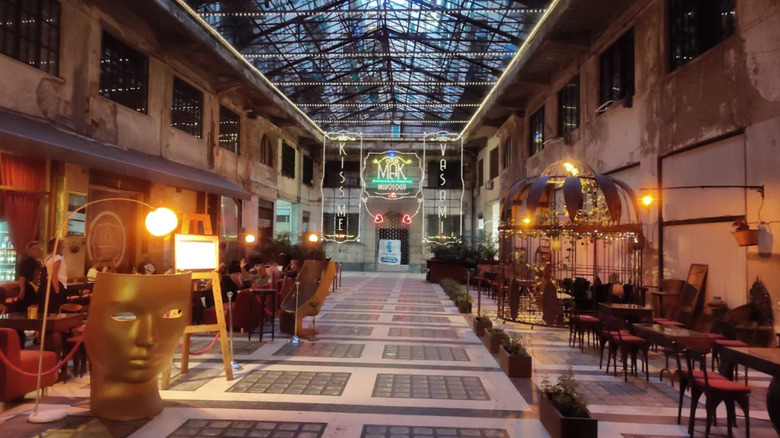 The large warehouse-like space with a glass ceiling and rows of tables at Mak Mixology in Palermo, Sicily