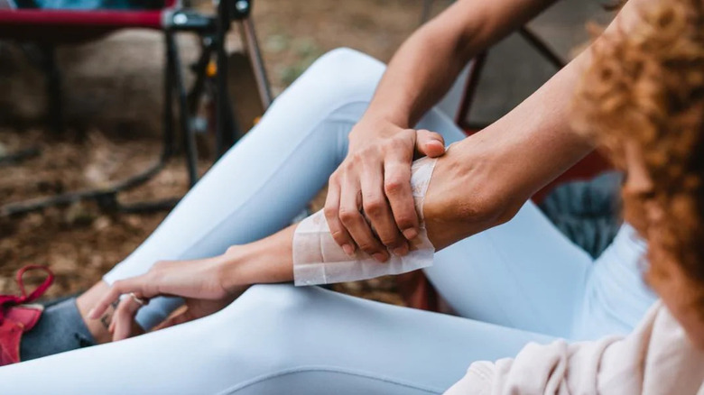 A camper wipes insect repellent onto her forearm using a towelette