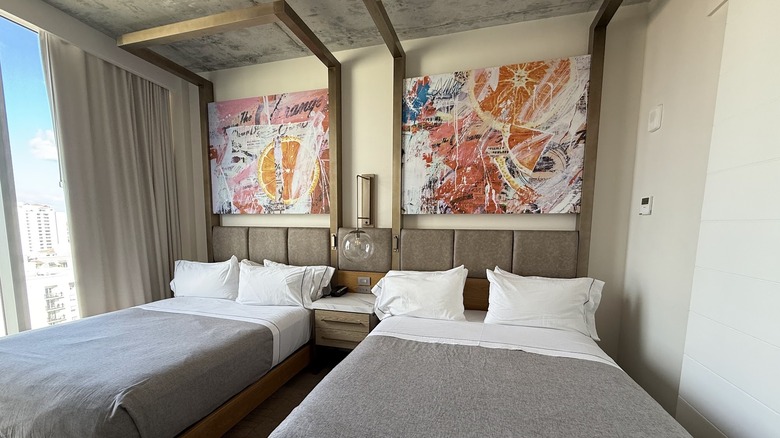 View of guest room with modern artwork and sleek beds with grey bedding at Canopy by Hilton hotel in West Palm Beach