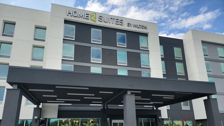 Exterior of modern Home2 Suites by Hilton Fort Walton Beach Eglin Air Force Base with signage visible and a blue sky in the background