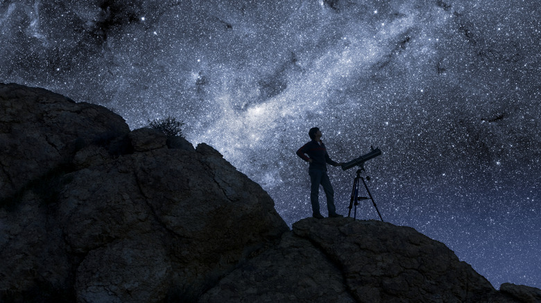 Man with telescope in front of Milky Way