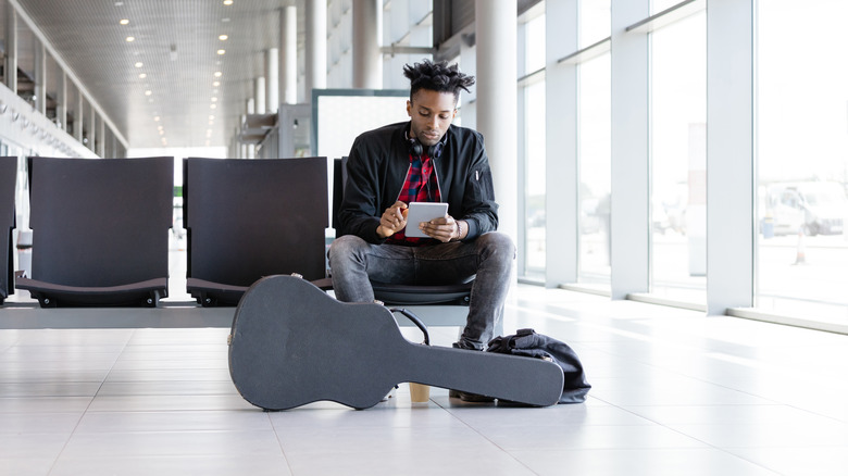Man with guitar at airport