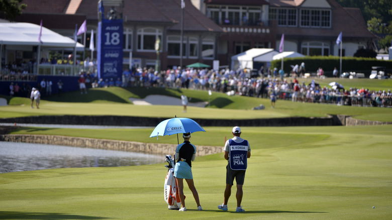 A female pro golfer and her caddy preparing for a shot during a PGA tournament in Johns Creek, GA.