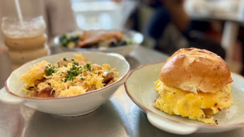 A breakfast sandwich, breakfast bowl, salad, and coffee on a table at Fred's