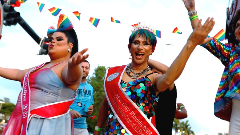 Drag queens smile with rainbow flags