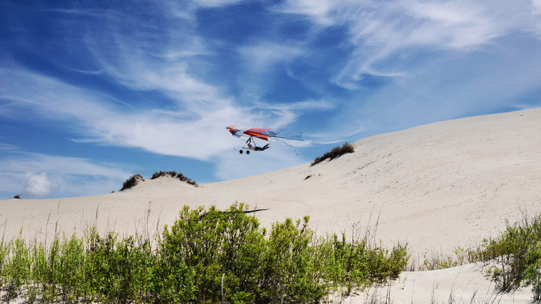 A hang glider flies over a dune at Jockey's Ridge State Park in North Carolina's Outer Banks