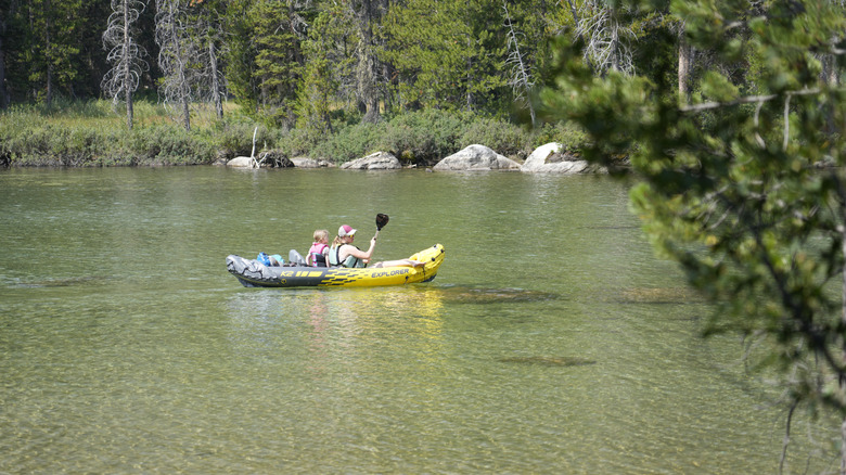 A woman and child canoeing on the water in String Lake surrounded by trees