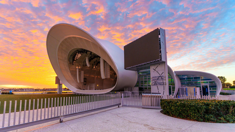 An exterior shot of Rady Shell in downtown San Diego, a modern elliptical building, set against a colorful sunset sky