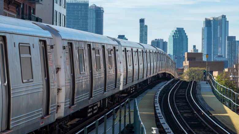 NYC subway train on tracks with skyscrapers around it