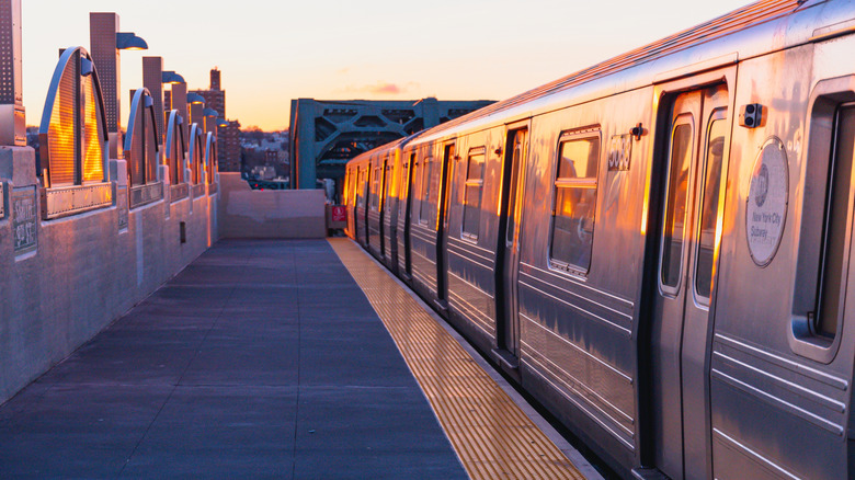 A subway train pulling into a station at sunrise in NYC