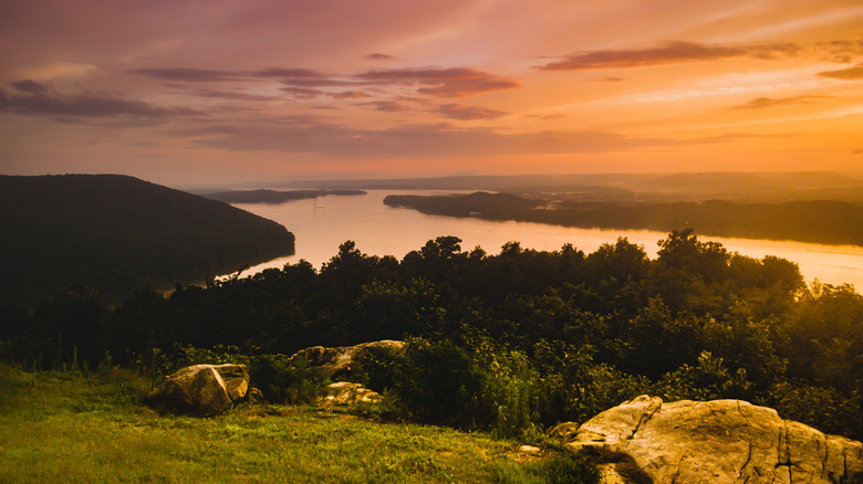 Sunset over the Tennessee River with trees and cliffs visible.