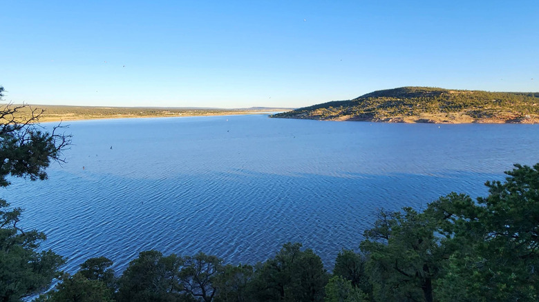 Expansive view of the bright blue water and verdant shoreline at Bluewater Lake State Park from above