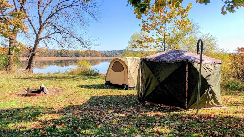 Two tents sit along a waterfront camping spot at Spruce Run Reservoir in New Jersey, surrounded by lake views and foliage.