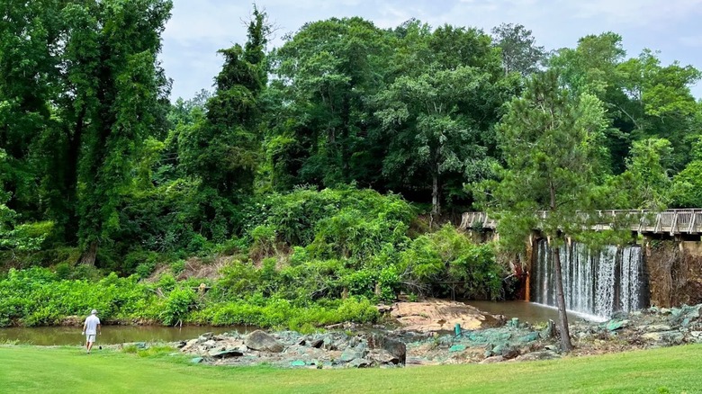 A scenic creek at Hard Labor Creek State Park in Georgia, featuring a bridge with a waterfall, surrounded by greenery.