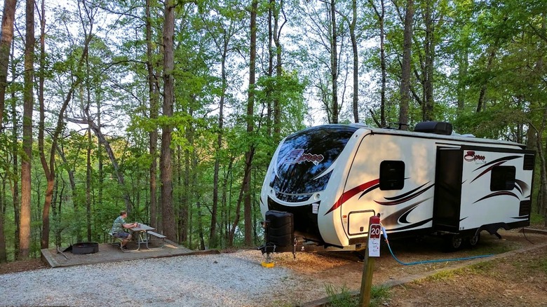 A modern camper parked in a wooded campground at Hard Labor Creek State Park in Georgia.