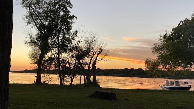 A boat on the shore and sunset over Lake Fayette Oak Thicket Park