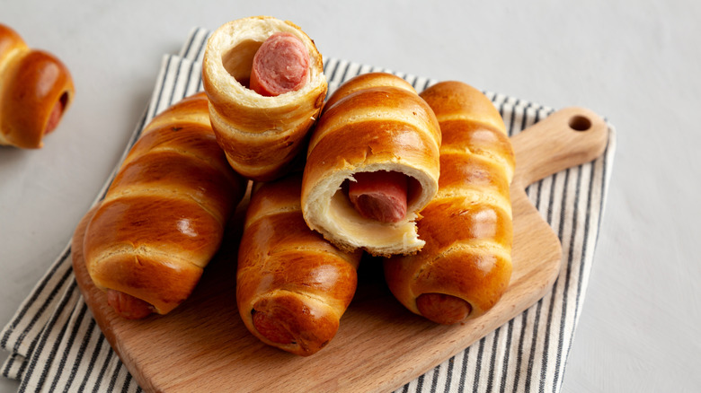 Traditional Czech sausage pastries on a wooden tray with a striped cloth underneath