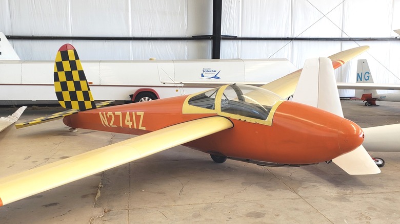An orange glider sits in a hangar at the Hamilton Soaring Club
