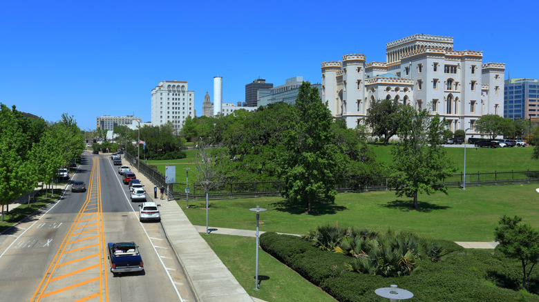 A street next to a park with Louisiana's Old State Capitol building in front of a blue sky