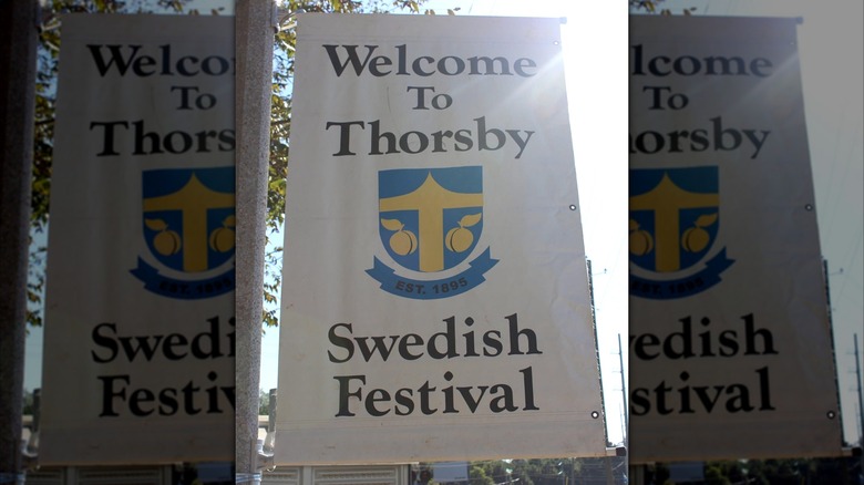 A white banner with the Thorsby town crest and the words Welcome to Thorsby Swedish Festival