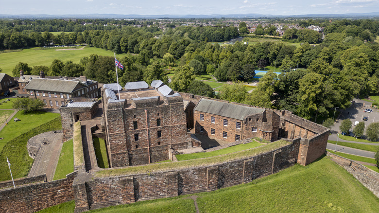 Silhouette of the gray stone and red sandstone castle on a mound, surrounded by trees