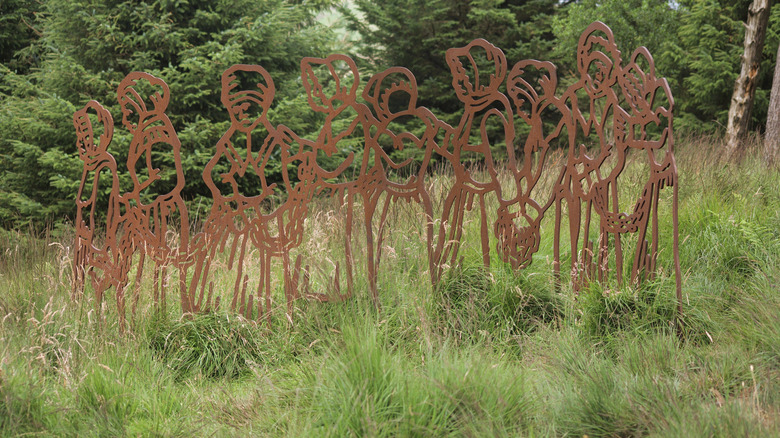 Copper-colored sculpture of women purported to be witches in the grass along the Pendle Sculpture Trail outside of Nelson